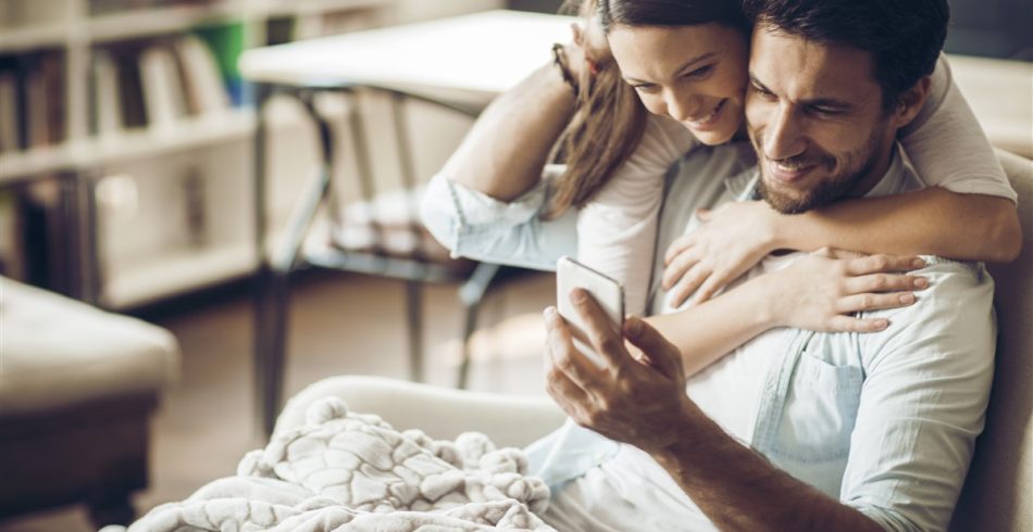 Couple_hugging_with_smartphone-950x490